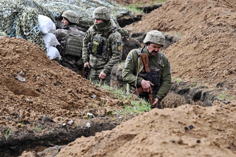 Ukrainian servicemen stand in a trench near their position near the town of Bakhmut on April 8, 2023.