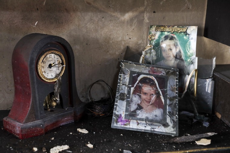 Portraits of an 11-year old girl killed by a Russian missile stand near the clock that stopped in the rocket attack in a damaged house in Zaporizhzhia, Ukraine, on April 9, 2023.