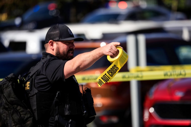 A police officer carries a roll of crime scene tape after a gunman opened fire at the Old National Bank building on April 10, 2023, in Louisville, Ky.