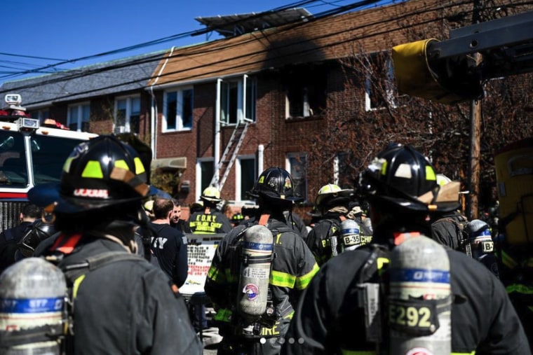 Firefighters gather outside a home in Queens, N.Y., after a fire broke out Monday.