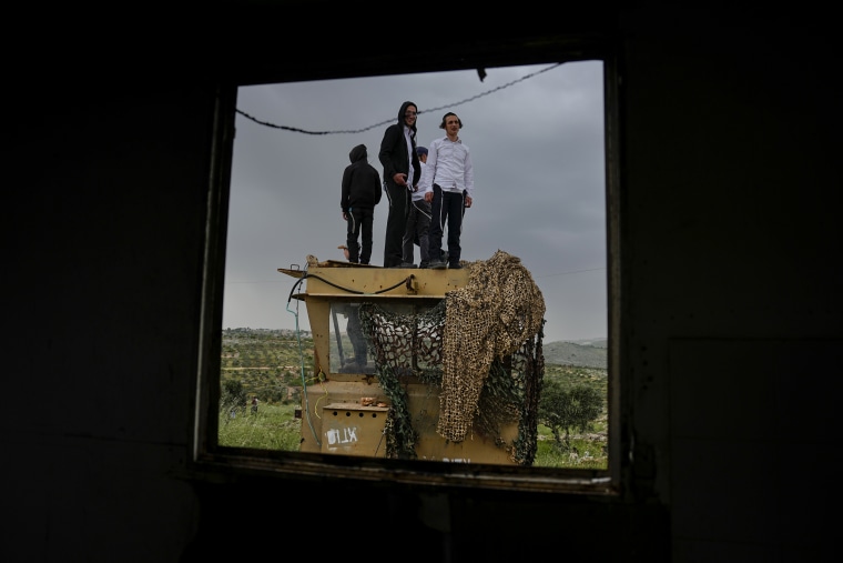 Israeli settlers stand in the outpost of Eviatar in the occupied West Bank on April 10, 2023.