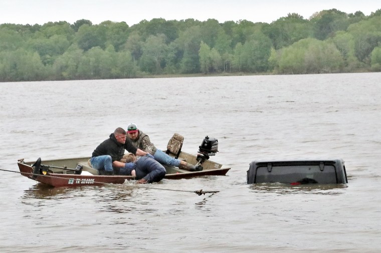 Two men rescue a woman from a submerged Jeep on the south side of Lake o’ the Pines in south west Marion County, Texas, on April 7, 2023.