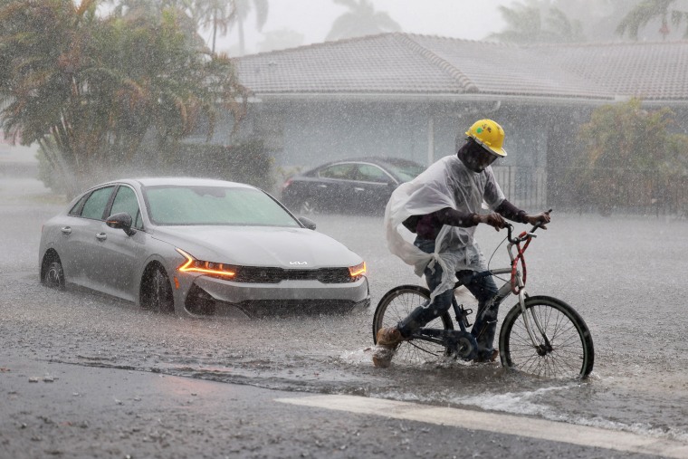 A biker passes stopped on a flooded road on April 12, 2023 in Dania Beach, Fla.