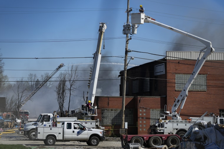 Utility workers remove utilities from the area as firefighter pour water on an industrial fire in Richmond, Ind., on April 12, 2023. 