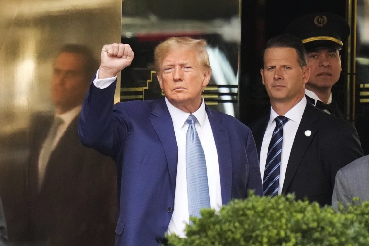 Former President Donald Trump raises a fist as he leaves Trump Towe