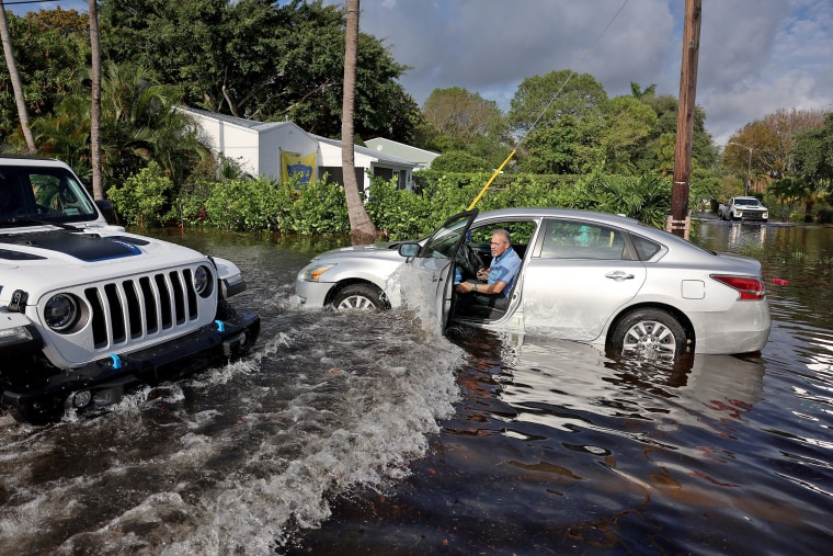 Angel Vega waits in his stalled car for a tow truck on April 13, 2023, in Hollywood, Fla., after record rains in the area. 