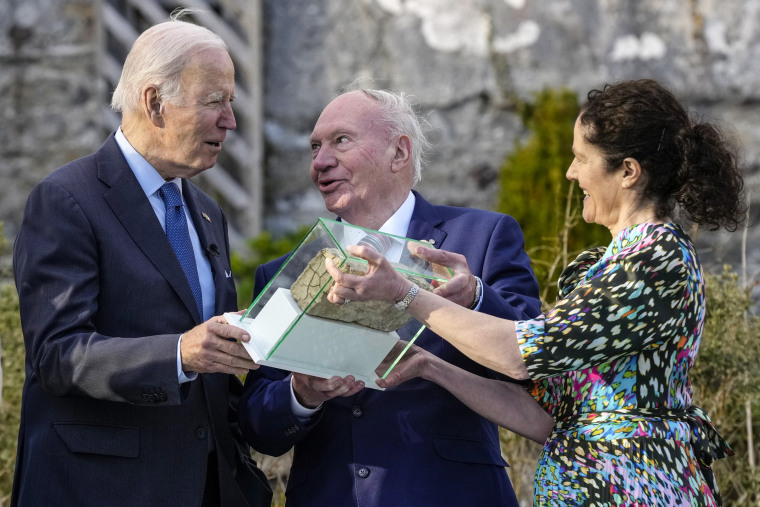 Image: Ernie Caffrey and his daughter Miriam Caffrey present President Joe Biden with a brick from the fireplace of the Blewitt family homestead as he visits the North Mayo Heritage Center in County Mayo, Ireland, on April 14, 2023.