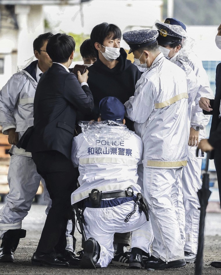 Image: A man, center, who threw what appeared to be a smoke bomb, is caught at a port in Wakayama, western Japan on April 15, 2023.