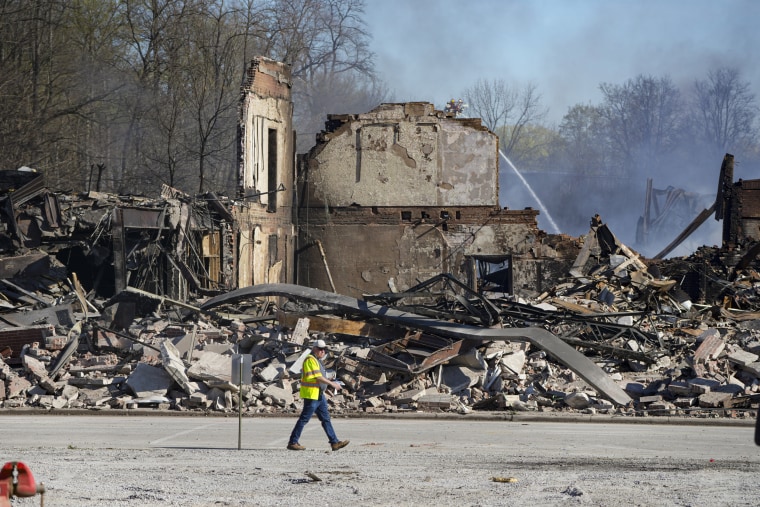 A worker walks past the rubble of an industrial fire that continued to burn in Richmond, Ind.