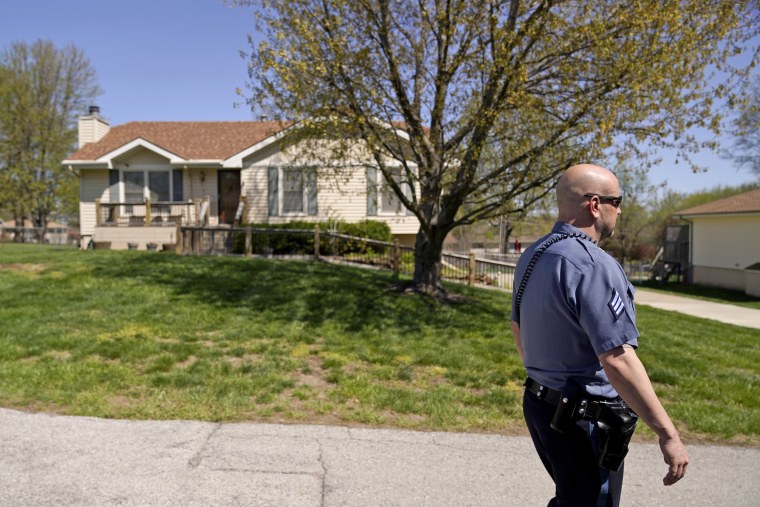 A police officer on April 17, 2023, walks past the house where 16-year-old Ralph Yarl was shot when he went to the wrong address to pick up his younger brothers in Kansas City, Mo.