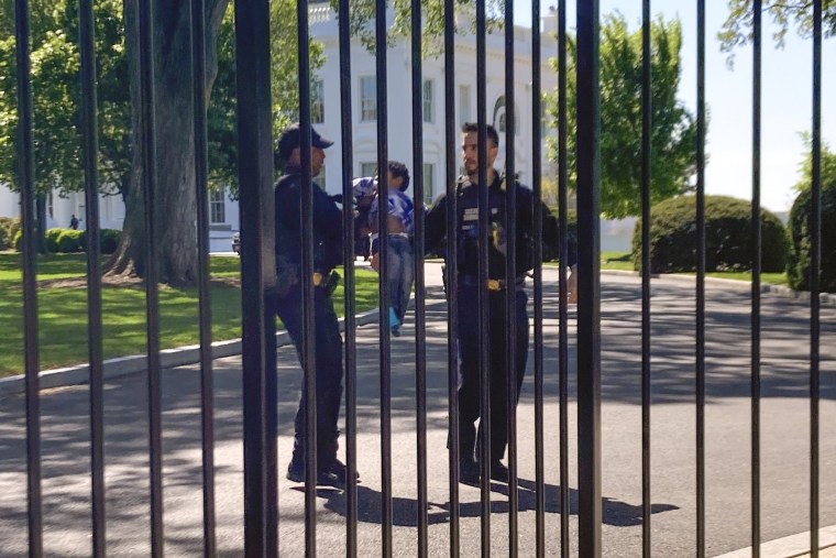 Secret Service officers carry a toddler who crawled through the White House fence