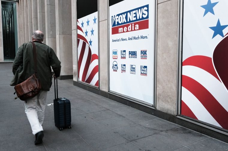People walk by the News Corporation headquarters, home to Fox News in New York