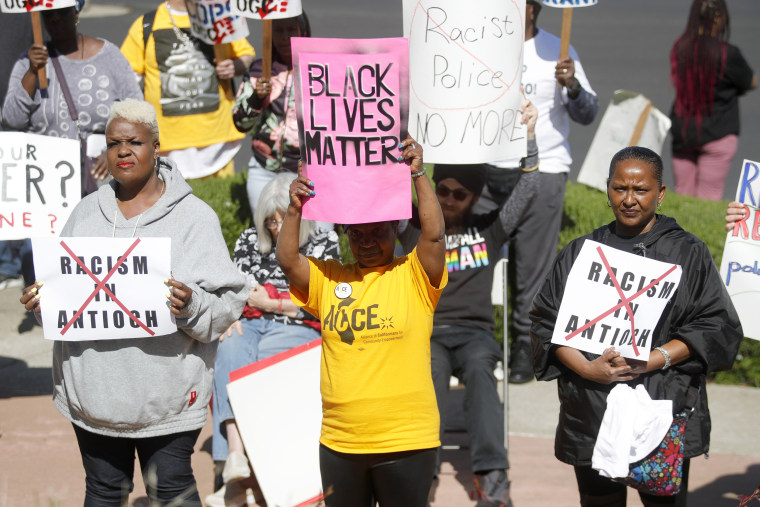 ANTIOCH, CALIFORNIA - APRIL 18: Community members including Della Currie, center, listen to civil rights attorney John Burris speak during a rally at Antioch police headquarters in Antioch, Calif., on Tuesday, April 18, 2023. Community members rallied and marched to City Hall to demand police reform and accountability following alleged racist, sexist and homophobic texts within the department.