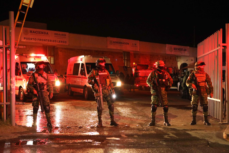 Firefighters and Mexican soldiers stand during a rescue for migrants from an immigration station in Ciudad Juarez, Mexico