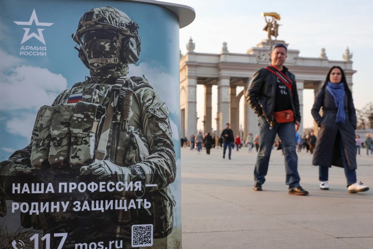 People walk past a desk promoting Russian army service in Moscow, Russia April 12, 2023.