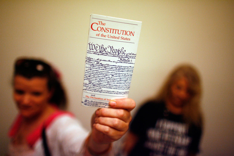 A woman holds up a copy of the U.S. Constitution at the Rayburn House Office Building on Capitol Hill, on July 25, 2008.
