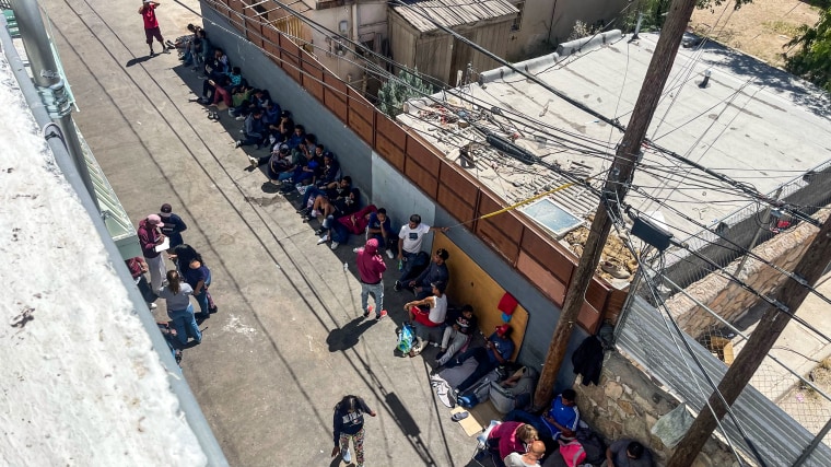 Migrants, many awaiting shelter, sit behind an alley outside the Opportunity Center for the Homeless in El Paso, Texas on April 26, 2023.