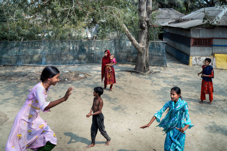 Children play as Sakila Akhtar, 12, carries her daughter Maria in Satkhira, Bangladesh.