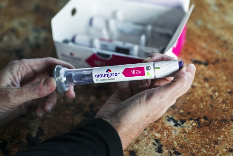 A woman holds a Mounjaro injectable pen at her home in Carlsbad, Calif.