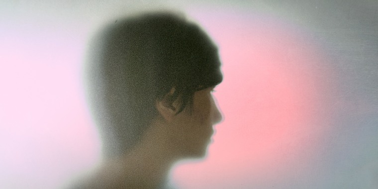 Silhouette of a woman's face against a grainy pink and grey gradient backdrop