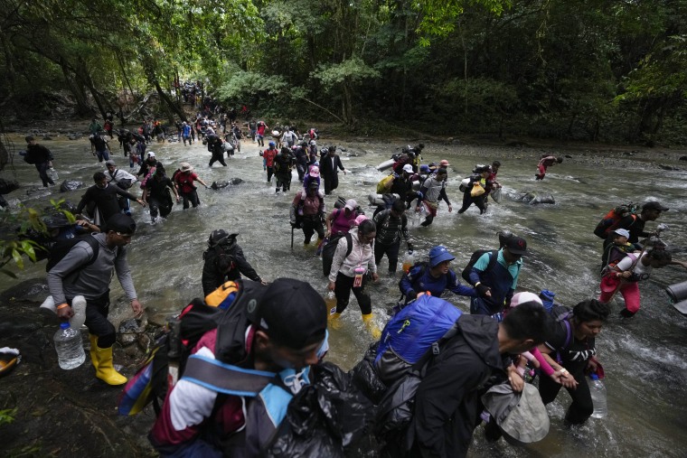 Migrantes, en su mayoría venezolanos, cruzan un río durante su viaje a través del Tapón del Darién desde Colombia hacia Panamá, con la esperanza de llegar a Estados Unidos, el 15 de octubre de 2022.