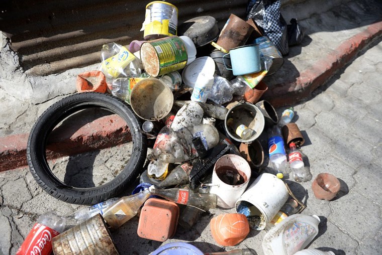 Foto de un neumático viejo, latas de aluminio y más basura acumulada siendo recogidas por autoridades de Guatemala en 2014 como parte de un esfuerzo de deshacerse de posibles criaderos de mosquitos transmisores de enfermedades