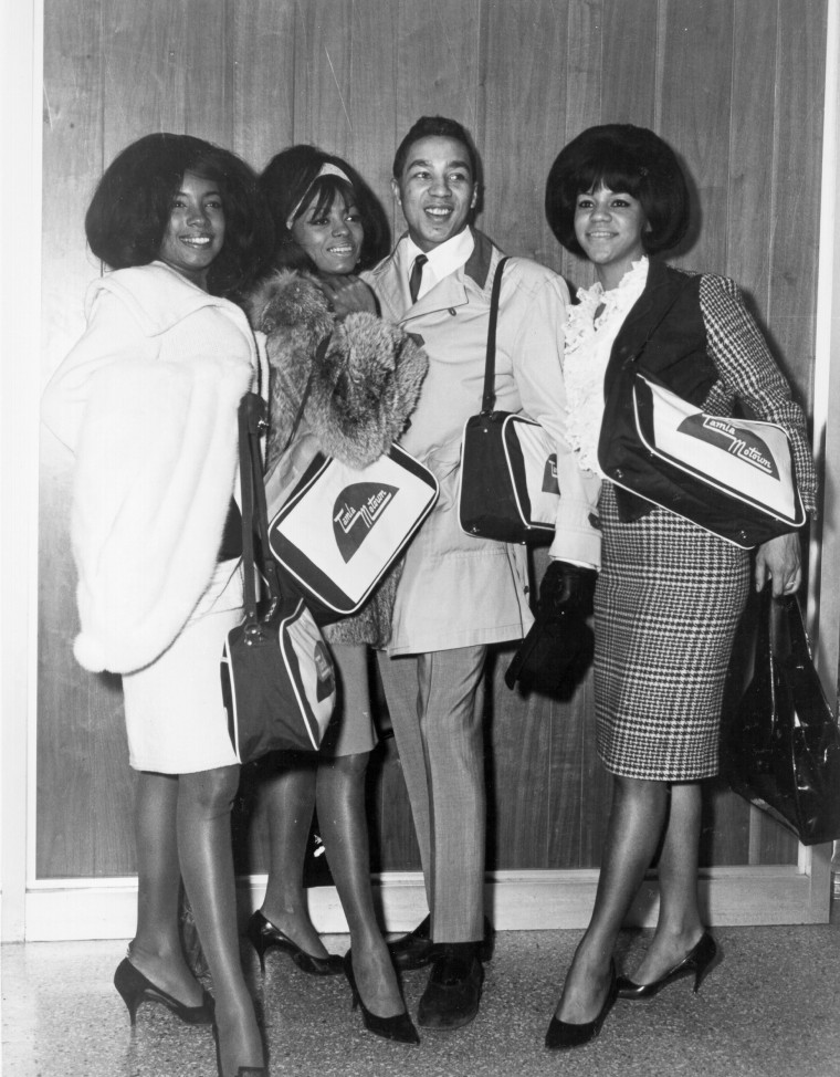 Mary Wilson, Diana Ross and Florence Ballard of the R&B vocal group "The Supremes" pose for a portrait with fellow Tamla Motown artist Smokey Robinson on March 15, 1965 wearing Tamla Motown bags arriving at Heathrow Airport on tour in London, England. 
