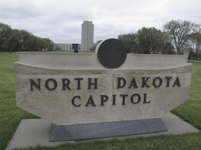 La torre del Capitolio de Dakota del Norte se eleva en el fondo detrás de una señal de piedra en Bismarck, Dakota del Norte, el 19 de abril de 2012.