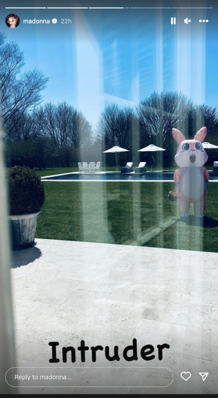 A person in a pink bunny costume. stands outside a home 