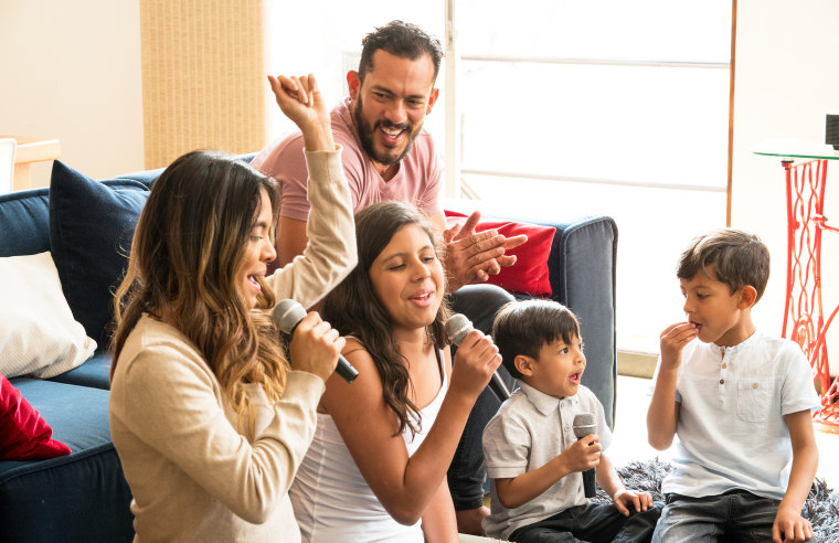 Family singing karaoke laughing and enjoying all together in the living room of his house.