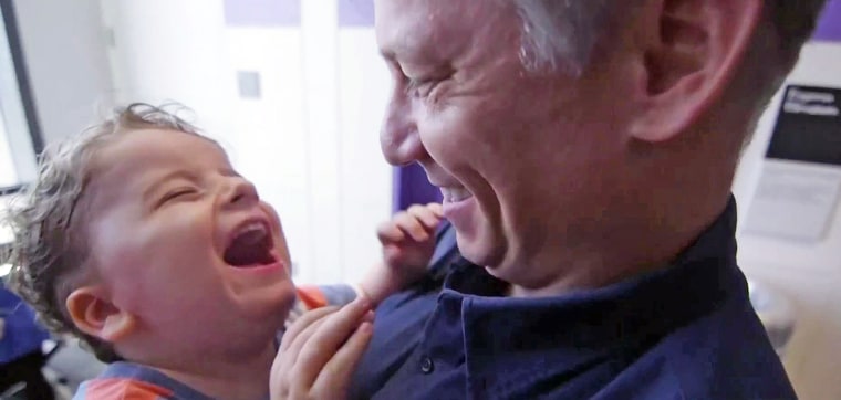 Henry Engel smiles and laughs as his father, Richard Engel, holds him.