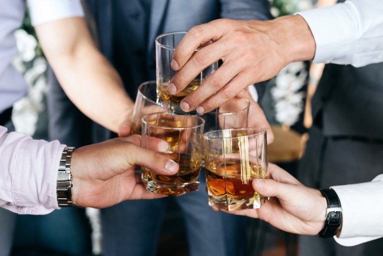 Group of guys friends with glasses of whiskey at a wedding.