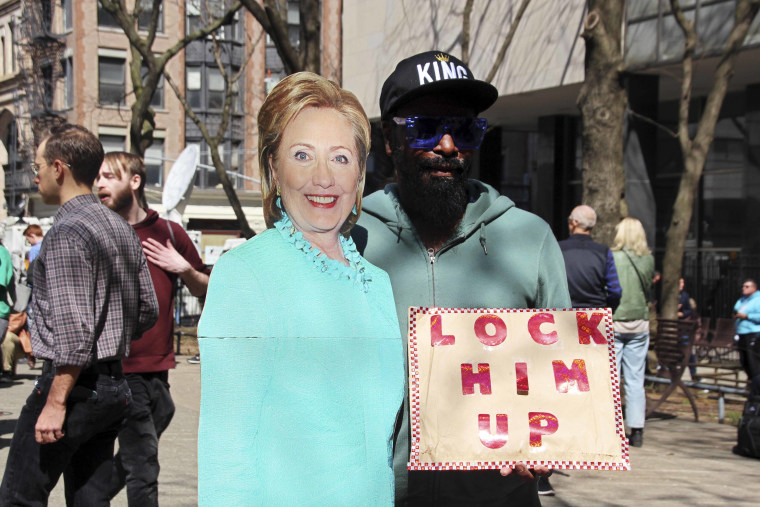 A protester holds a sign reading "Lock him up" in Collect Pond Park across the street from the Manhattan District Attorney's office during the arraignment of Donald Trump. 