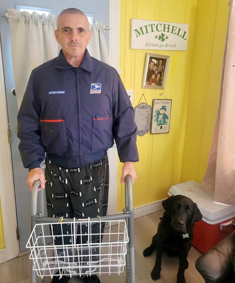 USPS worker Eddie Mitchell using a walker next to a black dog.