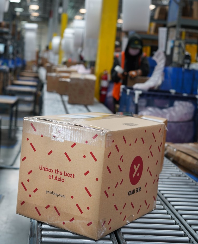 Une boîte avec un logo rouge sur un tapis roulant dans un entrepôt.
