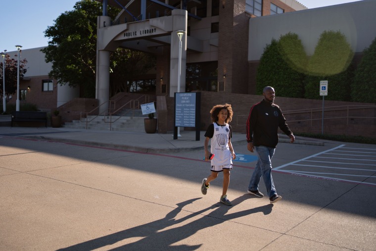 IMage: GCISD School board candidate Sergio Harris leaves Grapevine Library with his son on Saturday.