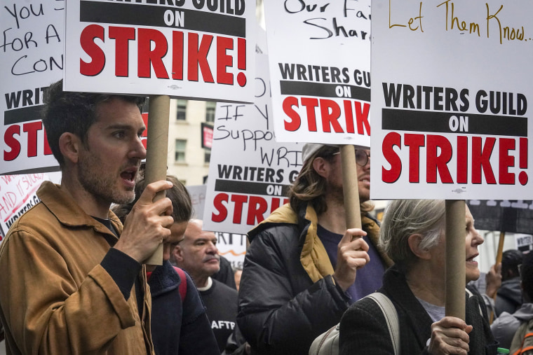 Striking writers hold signs as they march and picket calling for better wages, Tuesday, May 2, 2023, outside Peacock NewFront in New York.