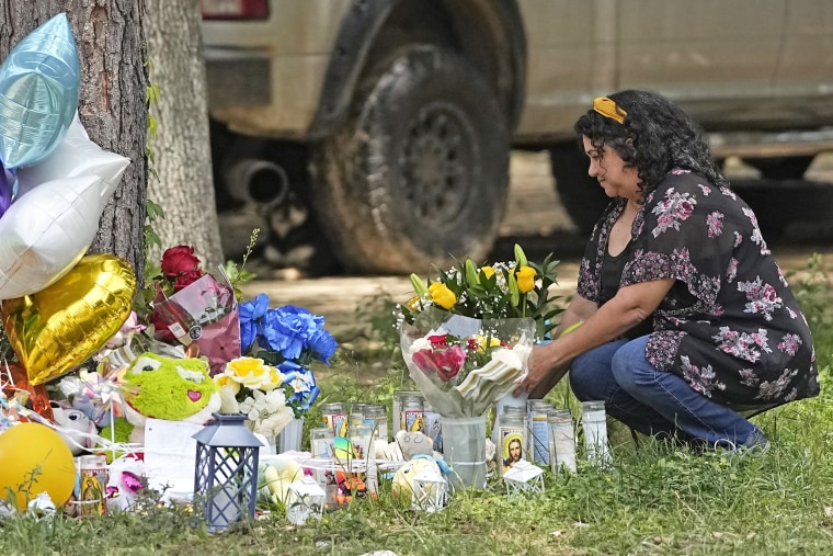 Maria Rodriguez places flowers Tuesday, May 2, 2023, outside the home where a mass shooting occurred Friday, in Cleveland, Texas. The search for the suspected gunman who allegedly shot five of his neighbors, including a child, after they asked him to stop firing off rounds in his yard stretched into a fourth day Tuesday.