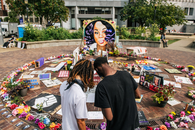 Two people look over a memorial dedicated to Breonna Taylor in Louisville, Ky.