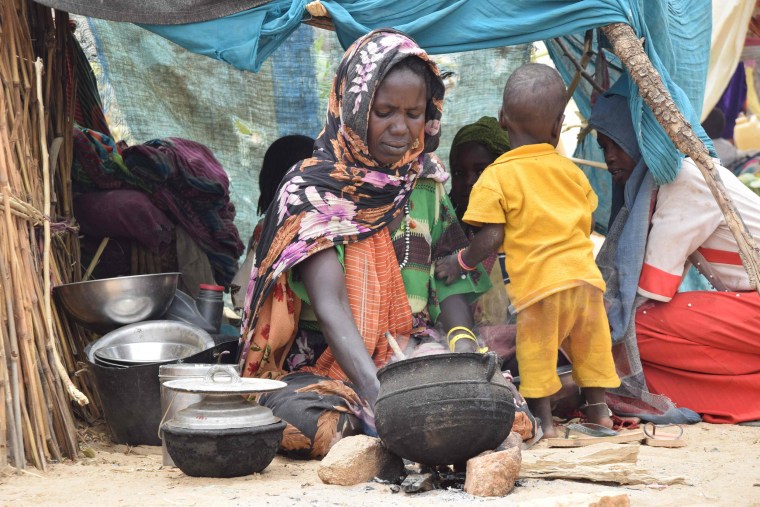 A Sudanese refugee who crossed into Chad cooks a meal in a makeshift shelter at a camp in Koufroun