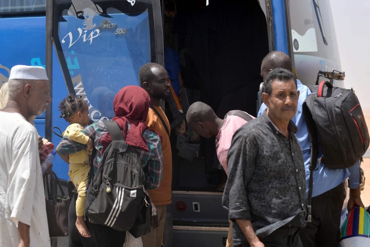 Sudanese refugees board a bus after crossing into Egypt