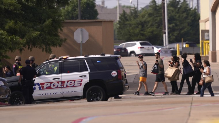 People raise their hands as they leave a mall following reports of a shooting, Saturday, May 6, 2023, in Allen, Texas. 