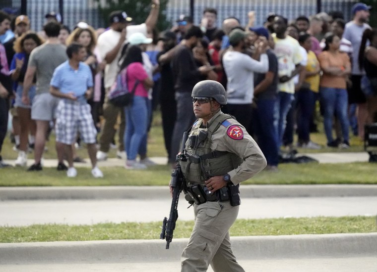 A law enforcement officer walks as people are evacuated from a shopping center where a shooting occurred Saturday, May 6, 2023, in Allen, Texas. 