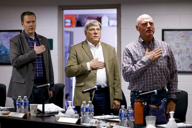 Woodland Park School Board Vice President David Illingworth II, left, Interim Superintendent Kenneth Witt, center, and President David Rusterholtz, right, say the Pledge of Allegiance before the start of the Board of Education meeting on April 12, 2023 in Woodland Park, Colo.
