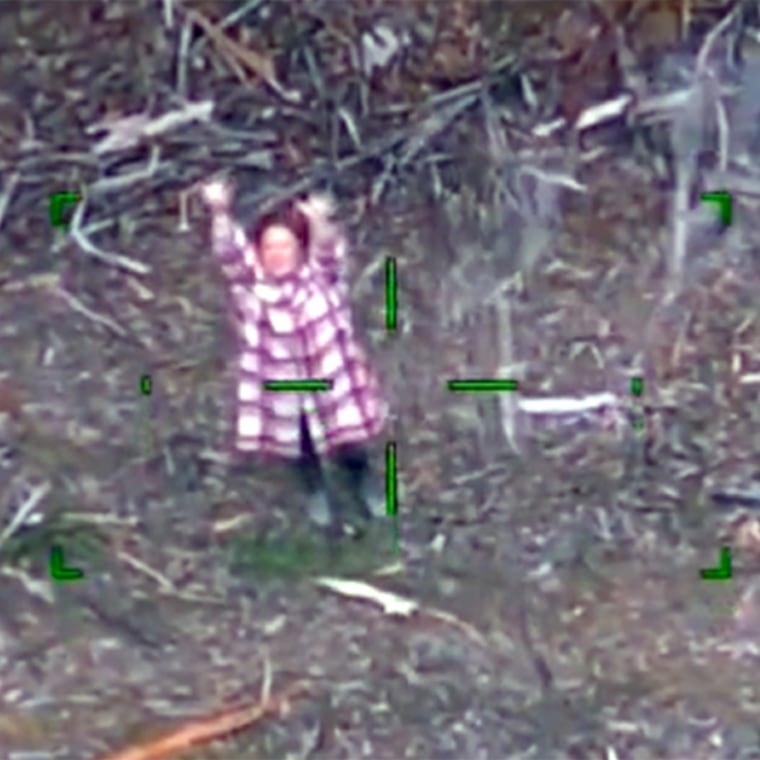 A woman waves to a rescue helicopter for help.