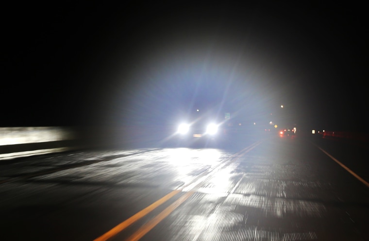 Bright lights from oncoming vehicle on a dark roadway