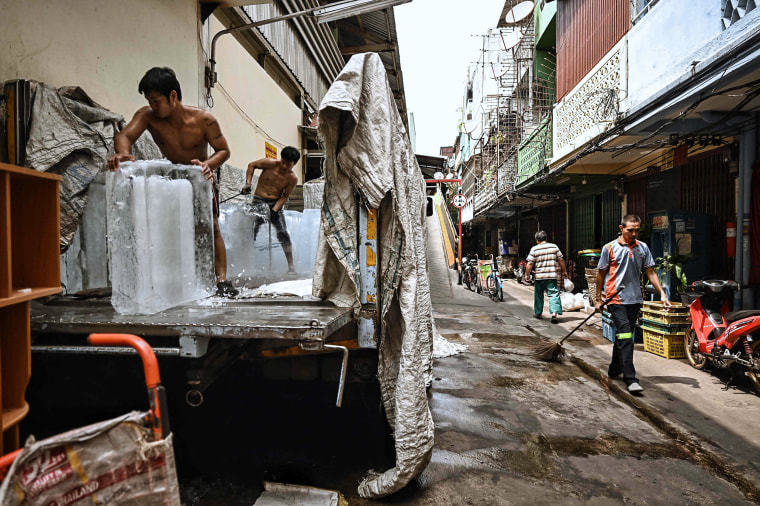 Image: Workers move blocks of ice into a storage unit at a fresh market during heatwave conditions in Bangkok on April 25, 2023.