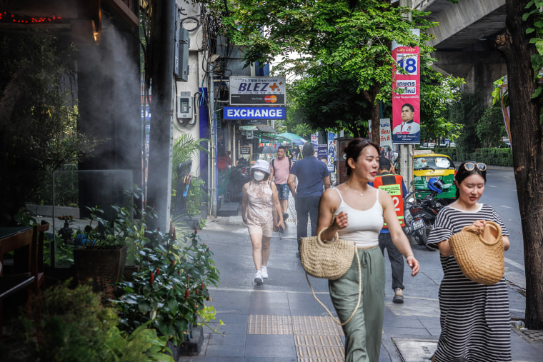 Pedestrians walk past a mist cooling system at a restaurant in Bangkok on April 25, 2023. 