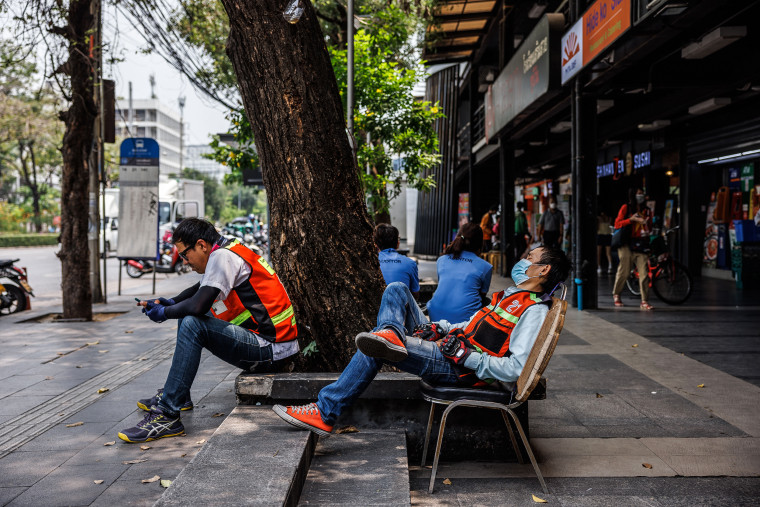 Motorbike taxi drivers rest in the shade during a heat wave in Bangkok on April 27, 2023. 