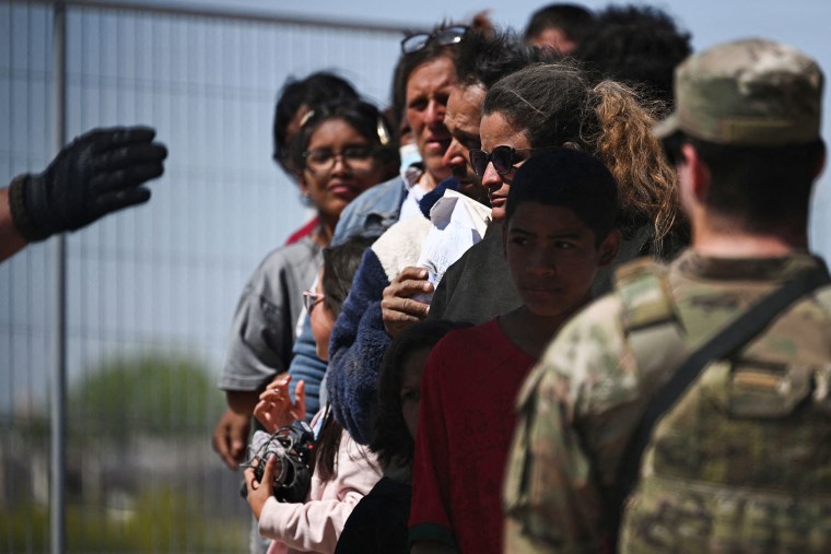 Un miembro de la Guardia Nacional del Ejército de Texas observa cómo los agentes de la Patrulla Fronteriza de Aduanas y Protección Fronteriza de EE. UU. buscan a los migrantes que viajan para el procesamiento de inmigración y asilo en la frontera entre EE. UU. y México en El Paso, Texas, el 10 de mayo de 2023. 